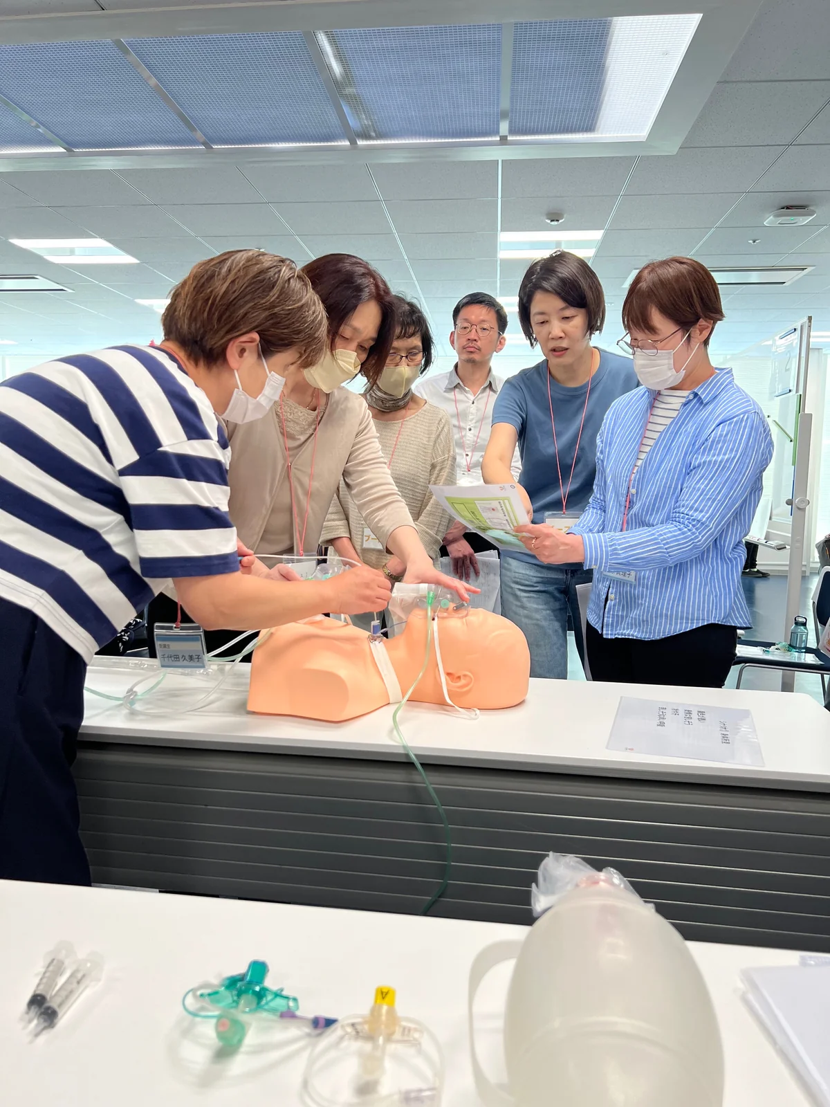 模型と器材を囲み、講師と参加者が一緒に気道緊急への対応を学ぶ場面